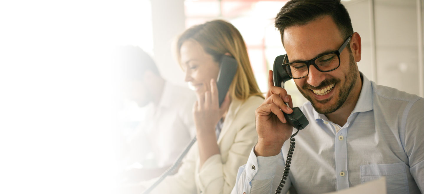 man talking on phone with other people talking on phones behind him